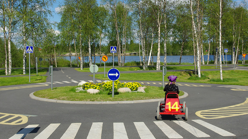 "Lapsi ajaa polkuautoa liikennepuistossa."