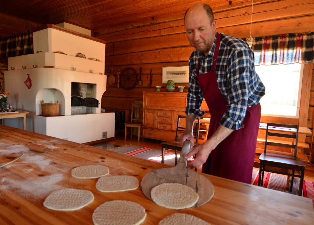 Mies nostaa leipomansa rieskan paistumaan pirtin leivinuuniin.