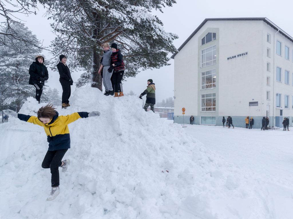 Nilon yläkoulun oppilaat viettävät ruokavälituntia koulun talvisella pihamaalla.