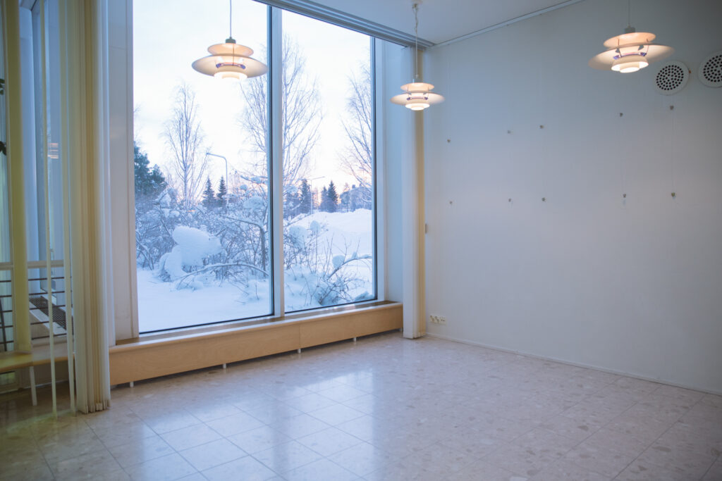 Kuvassa näkymä pikku-galleria Utun sisätiloihin. Huoneessa iso ikkuna, josta näkyy luminen maisema