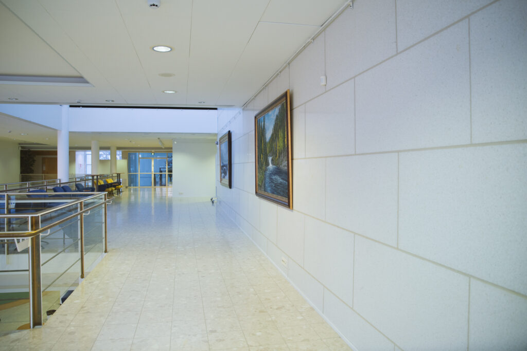 Kuvassa avautuu näkymä Kuusamotalon ylälämpiön käytävälle, jonka seinää voi käyttää näyttelytilana.