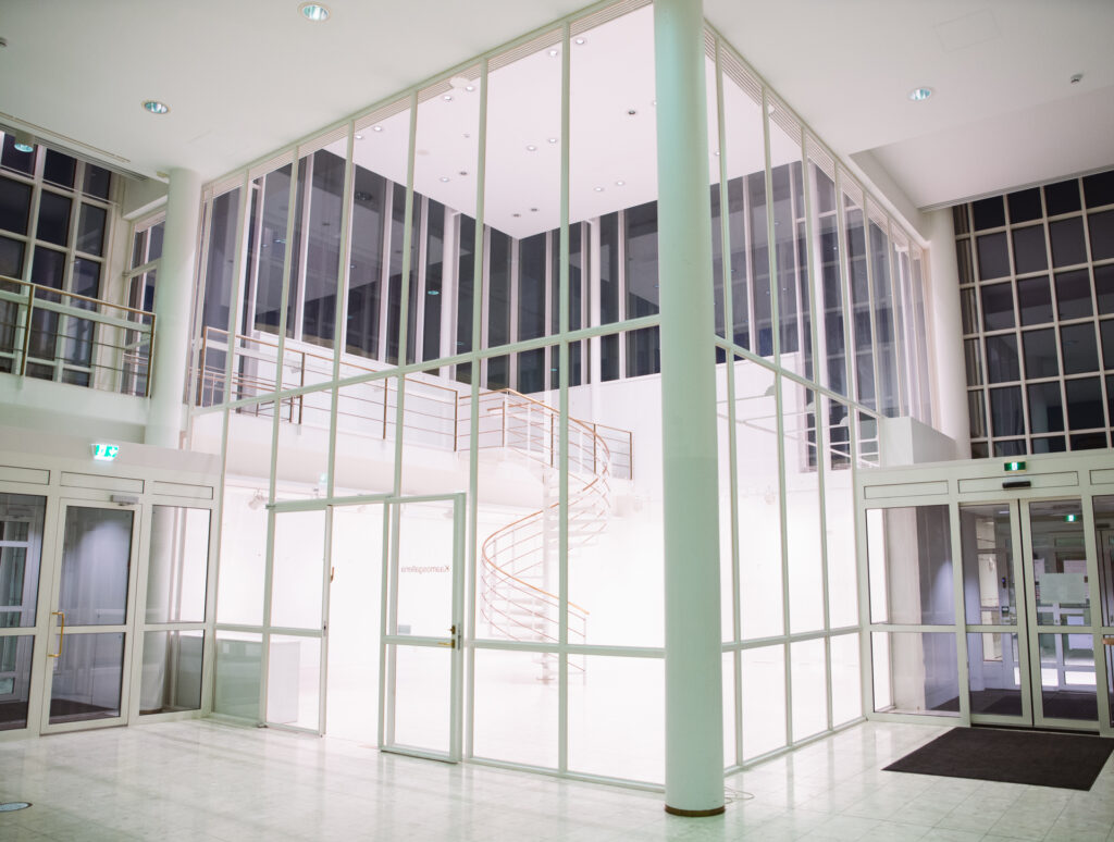Kuva otettu Kuusamotalon aulassa, ja siinä näkyy Kaamosgalleria, jossa on aulan puolella lasiset seinät lattiasta kattoon.
